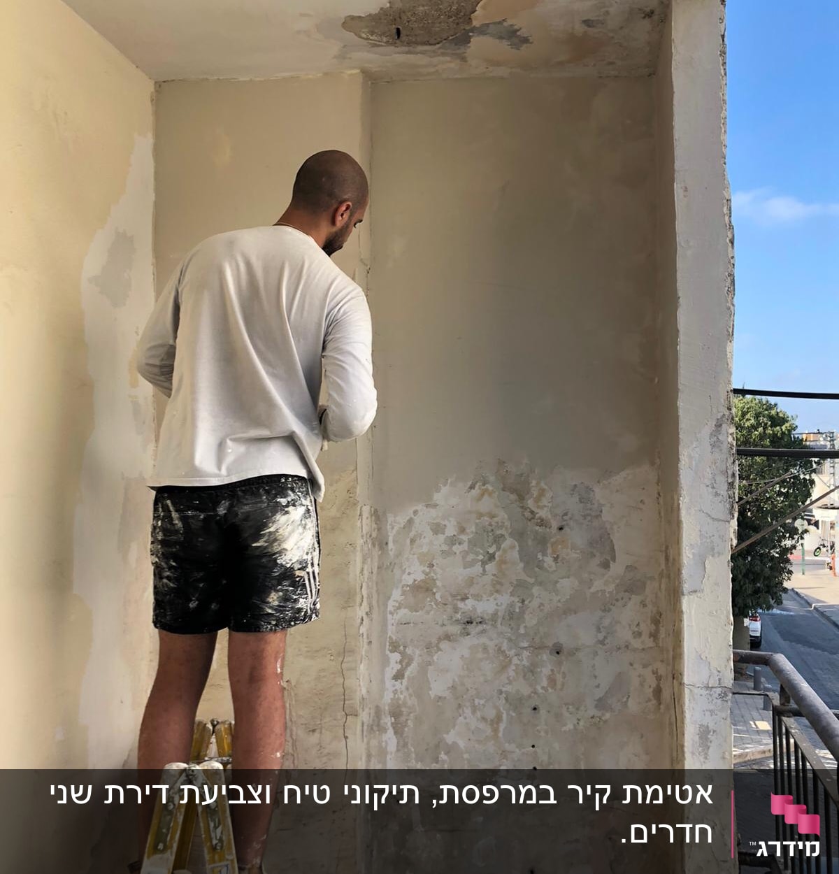 אדם עומד על סולם ומכין קיר לצביעה